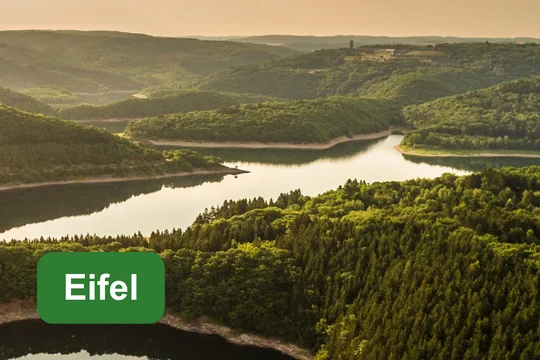 Eifel Urftalsperre im Nationalpark Eifel mit bewaldeten Hügeln und Textfeld ‚Eifel‘.