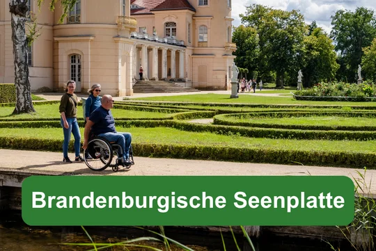 Brandenburgische Seenplatte Schloss Rheinsberg mit Schlossgarten und Person im Rollstuhl, dazu Textfeld ‚Brandenburgische Seenplatte‘.